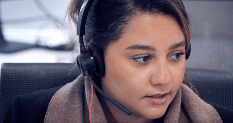 Opératrice de support informatique portant un casque micro, en conversation pour assister un utilisateur à distance.