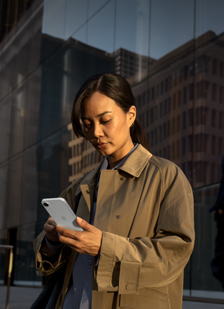 Une personne utilisant un iPhone 17e blanc pour poursuivre son travail en extérieur