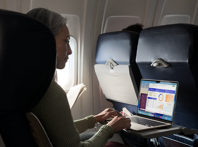 Personne assise dans un avion en train d’utiliser un MacBook Air pour montrer l’autonomie longue durée de l’appareil