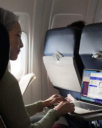 Personne assise dans un avion en train d’utiliser un MacBook Air pour montrer l’autonomie longue durée de l’appareil