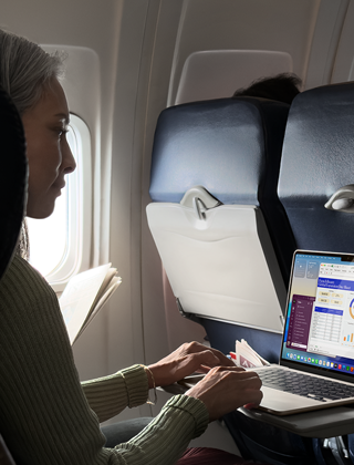 Personne assise dans un avion en train d’utiliser un MacBook Air pour montrer l’autonomie longue durée de l’appareil