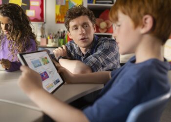 photo d'un professeur aidant un élève travaillant sur son iPad