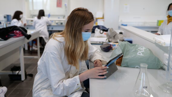 étudiante en blouse blanche travaillant sur iPad dans un laboratoire