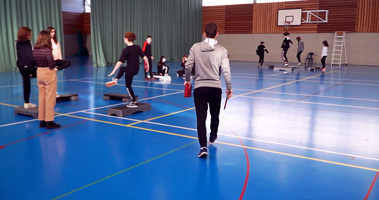 Photo d'un ensignant marchant dans un gymnase tandis que les élèves font des exercices