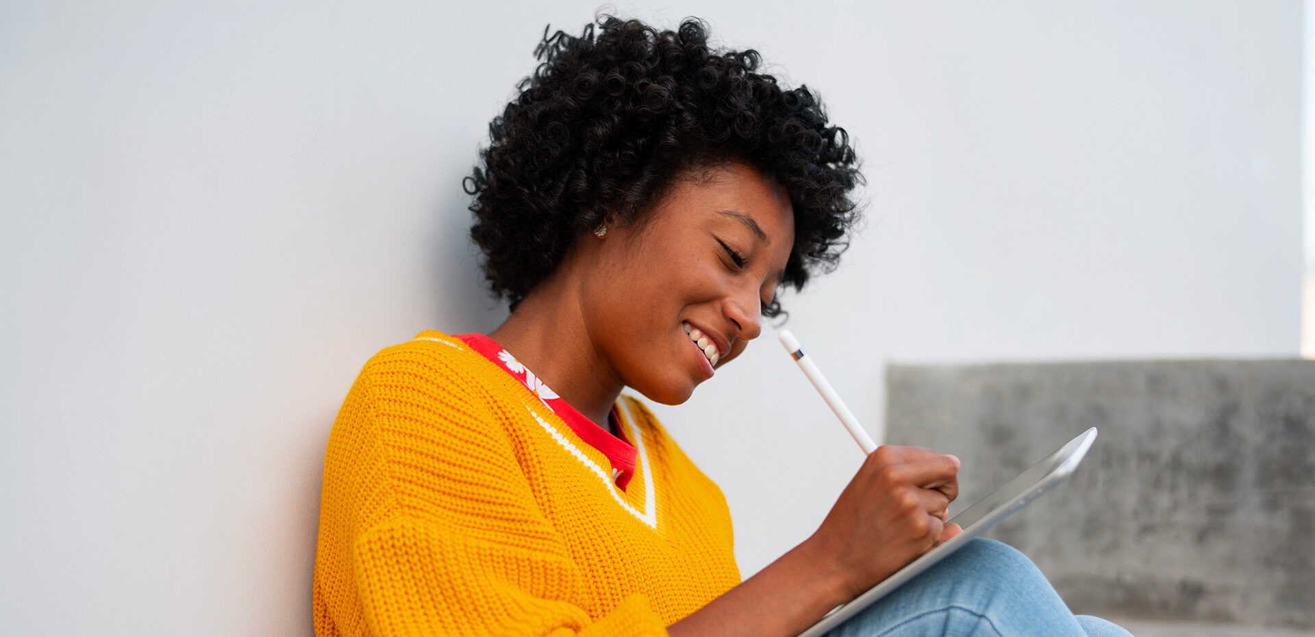 Photo d'une femme assise par terre écrivant avec son stylet sur son iPad